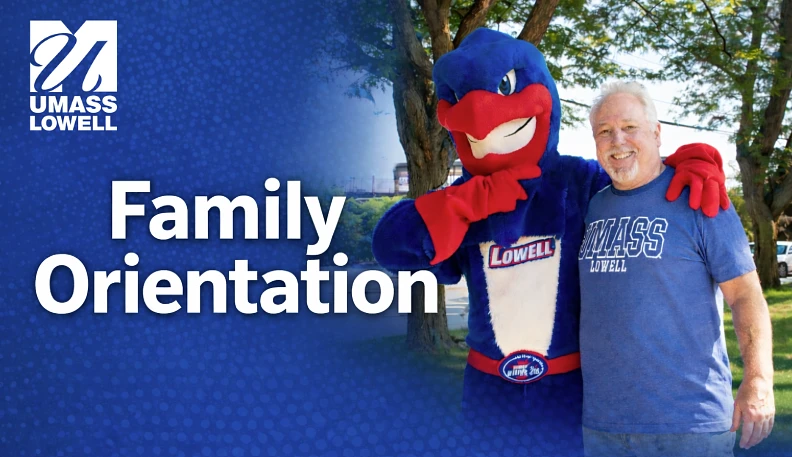 A person poses with a costumed mascot at a UMass Lowell Family Orientation event.